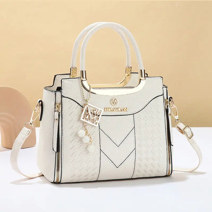 Dámska crossbody kabelka s prešívaním v tvare písmena V, kovaniami v zlatej farbe, viacerými priehradkami a hornou rukoväťou.