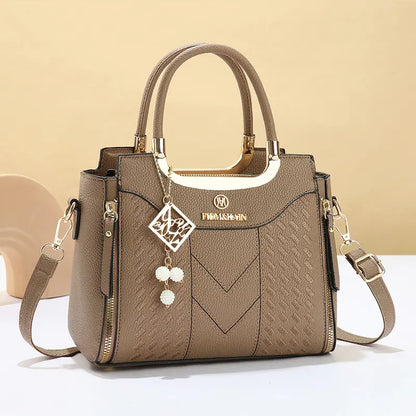 Dámska crossbody kabelka s prešívaním v tvare písmena V, kovaniami v zlatej farbe, viacerými priehradkami a hornou rukoväťou.
