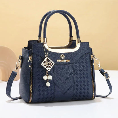 Dámska crossbody kabelka s prešívaním v tvare písmena V, kovaniami v zlatej farbe, viacerými priehradkami a hornou rukoväťou.
