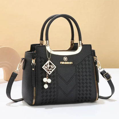 Dámska crossbody kabelka s prešívaním v tvare písmena V, kovaniami v zlatej farbe, viacerými priehradkami a hornou rukoväťou.